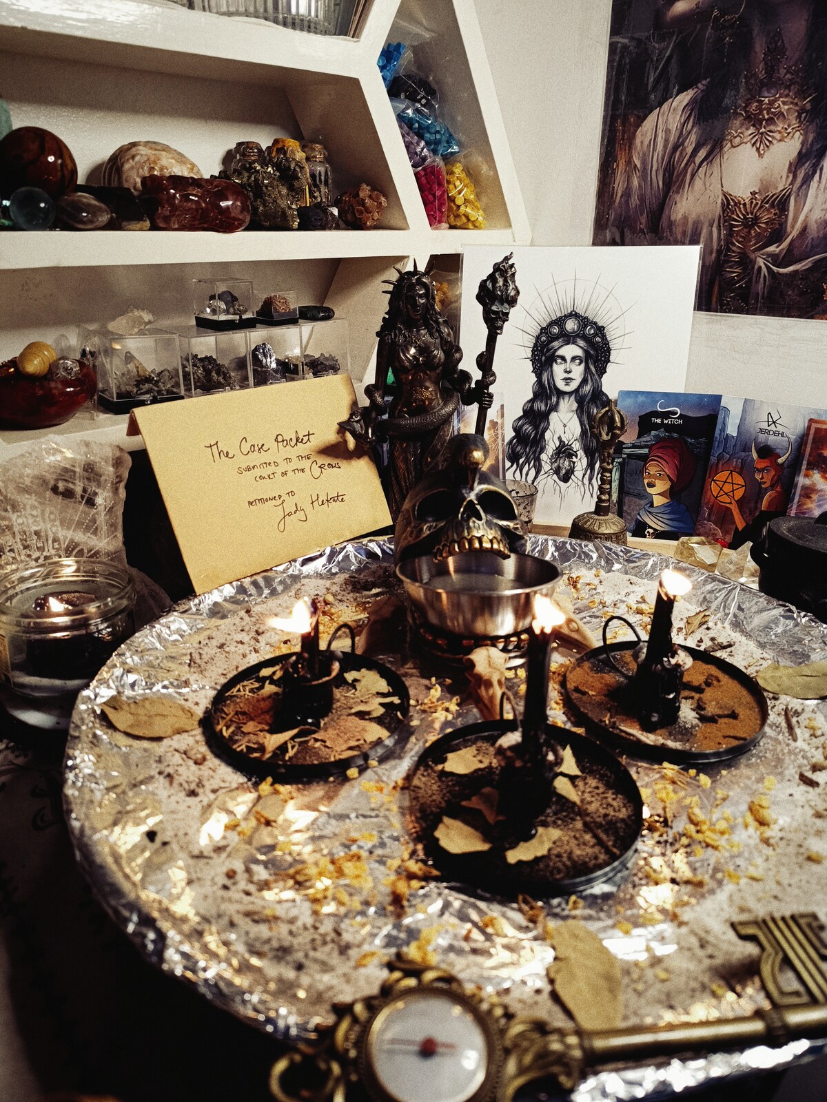 Court of the Crows justice altar with three burning petition candles, Hekate imagery, herbs, and the client case packet