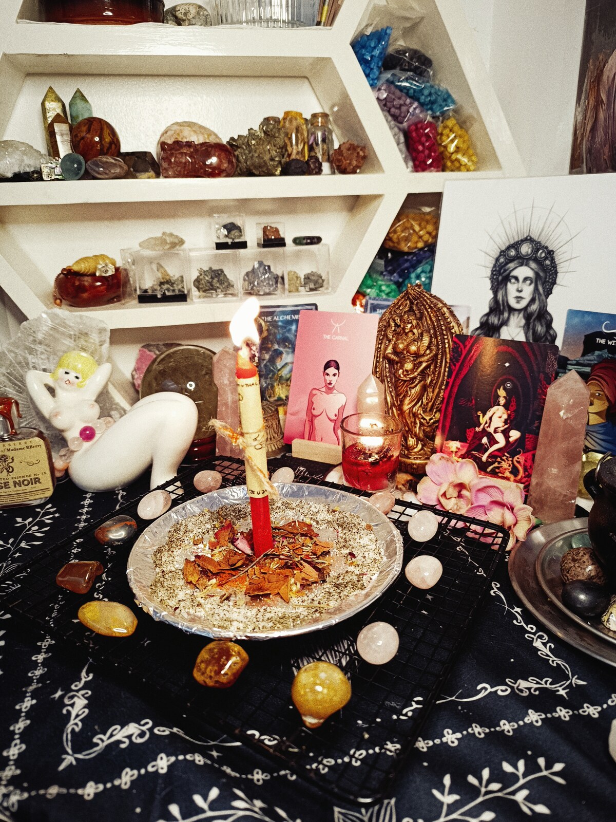 Hot Girl X Appeal altar with a burning petition candle, rose quartz, cards, flowers, and Lilith imagery